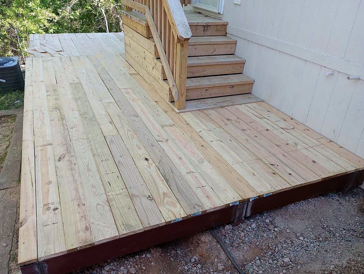 A newly built wood deck with steps leading up to a doorway.